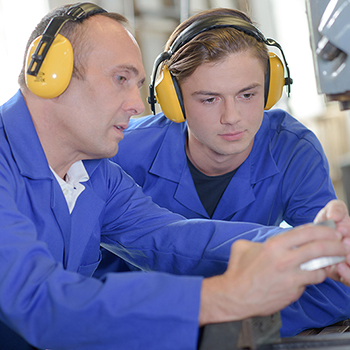 Two workers doing work while wearing ear protection