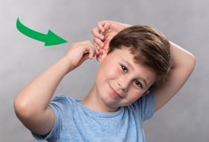 Screenshot of a GIF depicting young boy inserting a foam earplug.