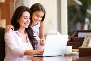 Una mujer y una niña mirando la pantalla de una computadora portátil.