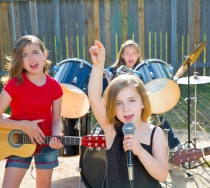 Blond kid singer girl singing playing live band in backyard concert with friends