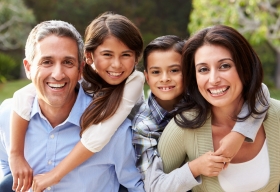 Un padre, una madre, hijo e hija sonriendo.